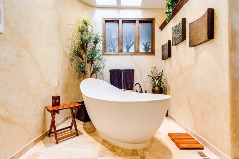 A bath tub in the center of a bathroom with plants