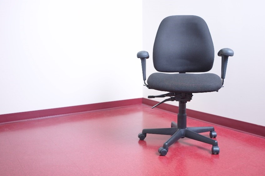 An ergonomic office chair on a red floor.